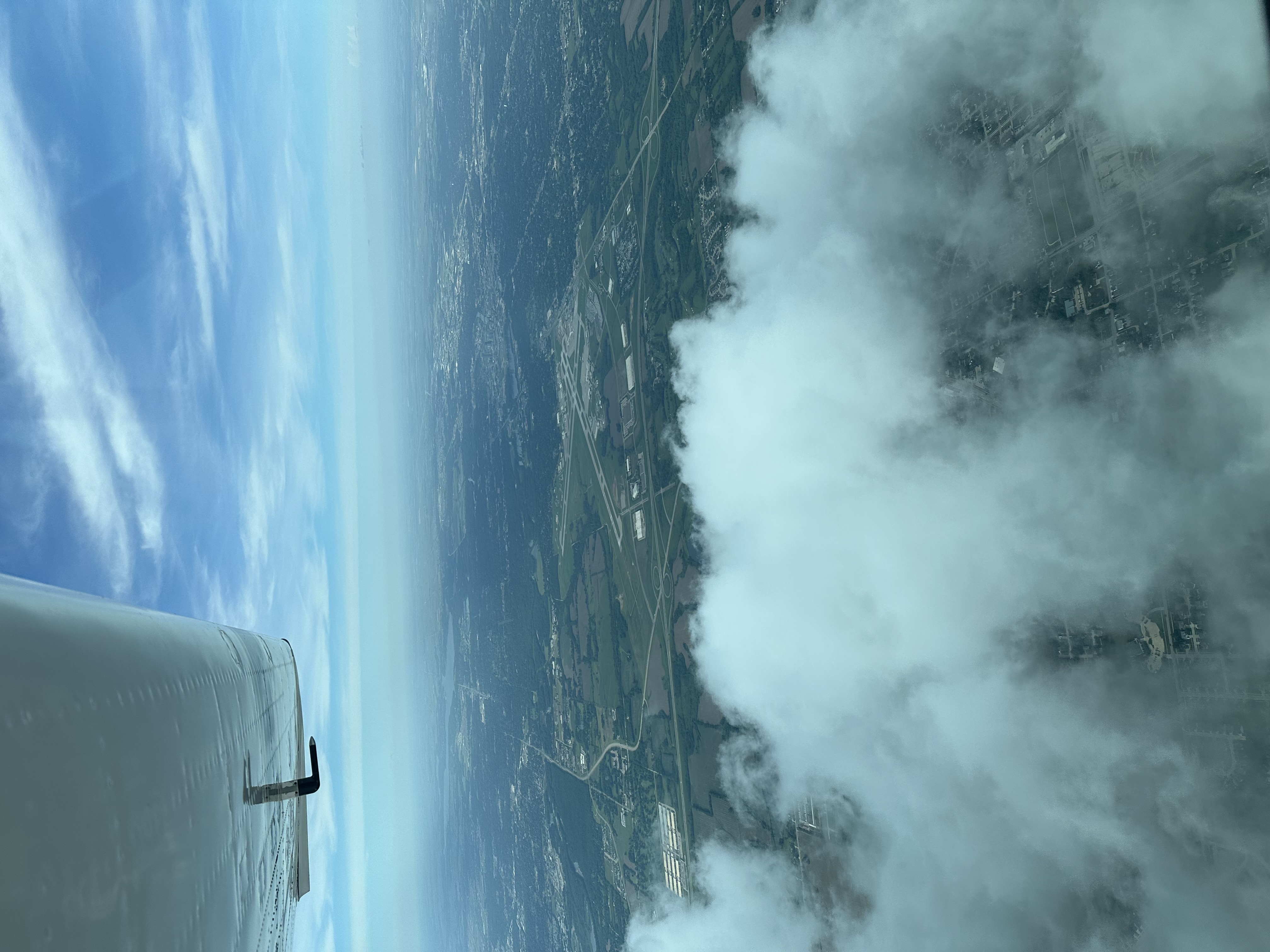 Aerial view from aircraft showing countryside and clouds below
